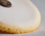 Un palet de dame, biscuit sablé glacé de blanc, orné d'un médaillon chocolat doré.
