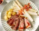 Tranches de viande juteuse avec asperges blanches et pommes de terre sautées, un accompagnement parfait pour un repas savoureux.
