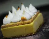 Une tranche de tarte au citron meringuée, avec sa crème jaune pâle, sa fine couche de biscuit et ses pointes de meringue légèrement caramélisées.