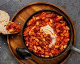 Délicieuse recette baked beans dans une poêle, garnie de crème, servie avec du pain grillé. Un plat réconfortant et savoureux.
