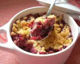 Cuillère de crumble fruits rouges, un délice croustillant et fruité dans un ramequin blanc.