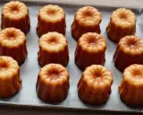 Douze mini cannelés dorés et caramélisés, prêts à être dégustés. Une recette facile pour des cannelés parfaits.