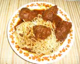 Un plat de spaghetti avec des ragoûts de bœuf en sauce, ressemblant à des alouettes sans tête, sur une assiette décorée de fleurs.