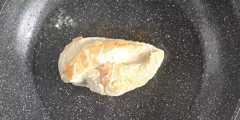 Escalope de poulet dorée dans une poêle, étape clé d'une recette facile et savoureuse.