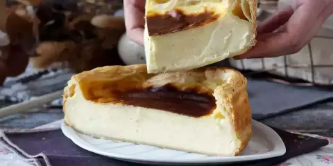 Un flan pâtissier aux bords dorés et à la crème onctueuse, une part est soulevée, révélant sa texture.