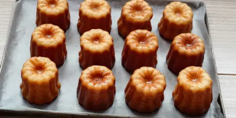Douze mini cannelés dorés et caramélisés, prêts à être dégustés. Une recette facile pour des cannelés parfaits.