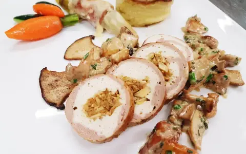 Délicieuse ballotine de volaille farcie, servie avec des champignons, des légumes croquants et une purée de pommes de terre gratinée.