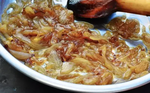 Oignons nouveaux caramélisés dans une poêle, prêts pour une délicieuse recette. La cuisson lente révèle leur douceur.