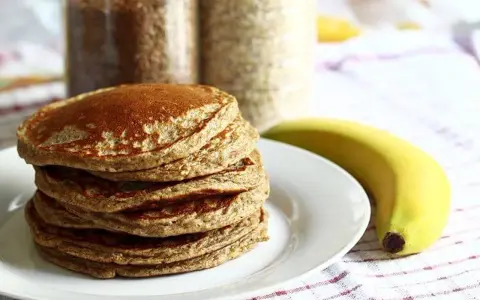 Pile de pancakes aux pois chiche, dorés et moelleux, accompagnés d'une banane. Parfait pour un petit-déjeuner sain.