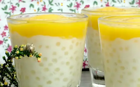 Trois verres de tapioca au lait de coco, surmontés d'une purée jaune, avec une petite branche de bruyère en premier plan.
