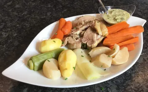 Tête de veau savoureuse accompagnée de carottes, pommes de terre et poireaux, le tout servi avec une sauce tartare crémeuse.