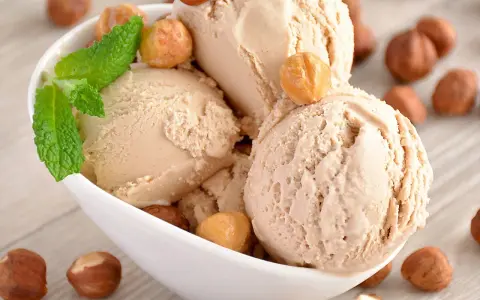 Gourmande recette glace noisette italienne. Boule crémeuse, garnie de noisettes grillées et d'une touche de menthe fraîche.