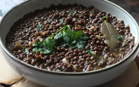 Un plat de cuisson lentilles vertes, garni de persil frais et d'une feuille de laurier.