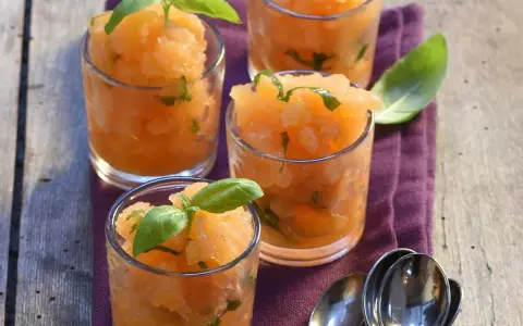 Recette soupe de melon apéritif : sorbet de melon frais aux feuilles de basilic dans des verres, prêt à déguster.