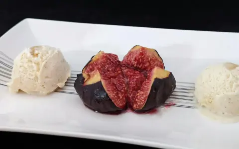Une figue fraîche coupée en deux, servie avec deux boules de glace à la vanille. Un aperçu des 15 recettes étonnantes à la figue fraîche.