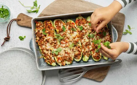 Courgettes farcies à la viande hachée, gratinées au fromage et garnies de feuilles de basilic frais. Un plat savoureux prêt à être dégusté.