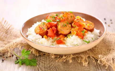 Un plat de rougail saucisse sur du riz blanc, garni de persil. Quel vin avec rougail saucisse ? Un vin fruité et léger serait parfait.