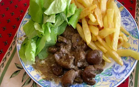 Assiette de rognon de boeuf en sauce, frites dorées et salade verte fraîche. Un plat savoureux pour les amateurs de gibier.