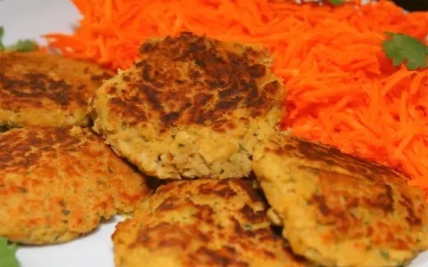 Galettes de pois chiche dorées et croustillantes, servies avec une généreuse portion de carottes râpées fraîches. Un délice végétarien !
