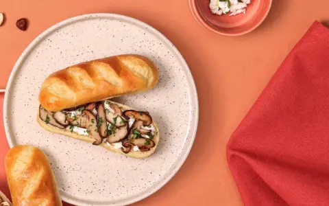 Délicieux sandwich pain au lait garni de champignons sautés et de fromage frais, parsemé de persil.