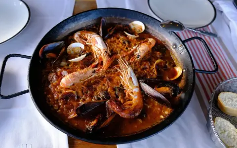 Un plat de vin avec paella aux crevettes et moules, prêt à être dégusté.