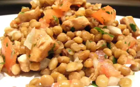 Salade de lentilles et poulet, garnie de dés de tomates et d'herbes fraîches. Un plat sain et savoureux.