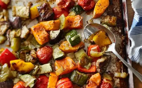Un délicieux mélange de légumes au four : courgettes, poivrons, tomates cerises, patates douces et aubergines, assaisonnés et rôtis à la perfection.