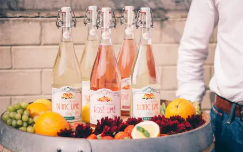 Bouteilles de cocktail vin blanc limonade citron, fruits frais et fleurs dans un tonneau.