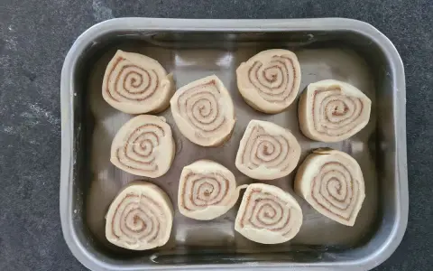 Dix roulés à la cannelle prêts pour la cuisson, une étape clé de la recette de cinnamon rolls.