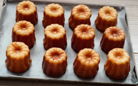 Douze mini cannelés dorés et caramélisés, prêts à être dégustés. Une recette facile pour des cannelés parfaits.