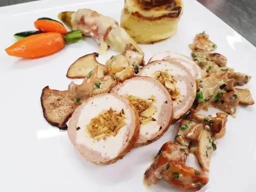Délicieuse ballotine de volaille farcie, servie avec des champignons, des légumes croquants et une purée de pommes de terre gratinée.