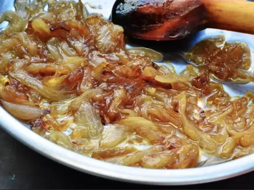 Oignons nouveaux caramélisés dans une poêle, prêts pour une délicieuse recette. La cuisson lente révèle leur douceur.