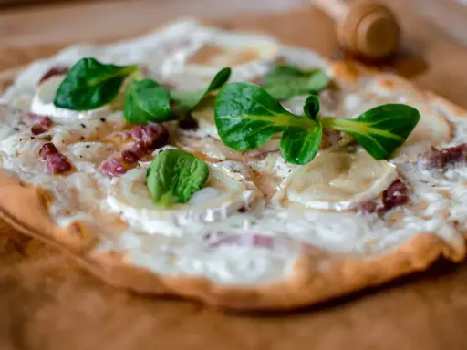 Délicieuse tarte flambée végétarienne garnie de fromage de chèvre, oignons et herbes fraîches.