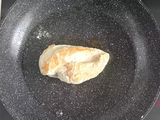Escalope de poulet dorée dans une poêle, étape clé d'une recette facile et savoureuse.