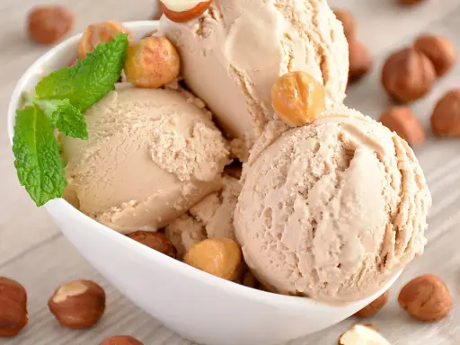 Gourmande recette glace noisette italienne. Boule crémeuse, garnie de noisettes grillées et d'une touche de menthe fraîche.