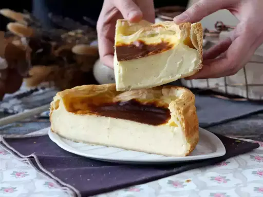 Un flan pâtissier aux bords dorés et à la crème onctueuse, une part est soulevée, révélant sa texture.