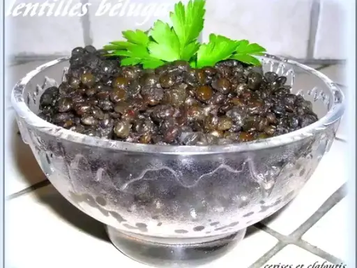 Lentilles beluga, parfaitement cuites, servies dans un bol en verre, garnies de persil frais. Un délice simple et sain.