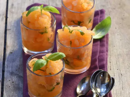 Recette soupe de melon apéritif : sorbet de melon frais aux feuilles de basilic dans des verres, prêt à déguster.