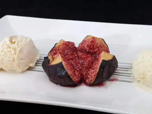 Une figue fraîche coupée en deux, servie avec deux boules de glace à la vanille. Un aperçu des 15 recettes étonnantes à la figue fraîche.