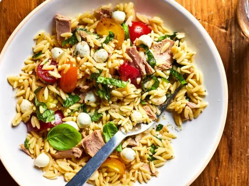 Salade de pâtes orzo avec thon, tomates cerises, billes de mozzarella et basilic frais, parfaite pour un pique-nique ensoleillé.
