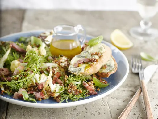 Salade verte avec chou-fleur rôti, lentilles, lardons et toasts au fromage bleu. Une idée de quoi mettre dans une salade verte pour un repas savoureux.