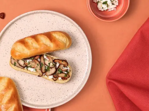 Délicieux sandwich pain au lait garni de champignons sautés et de fromage frais, parsemé de persil.