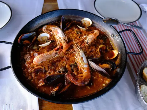 Un plat de vin avec paella aux crevettes et moules, prêt à être dégusté.