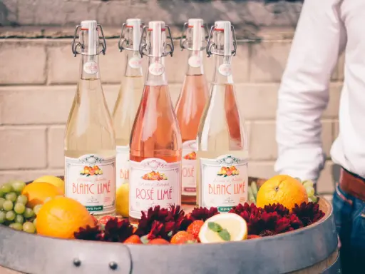 Bouteilles de cocktail vin blanc limonade citron, fruits frais et fleurs dans un tonneau.