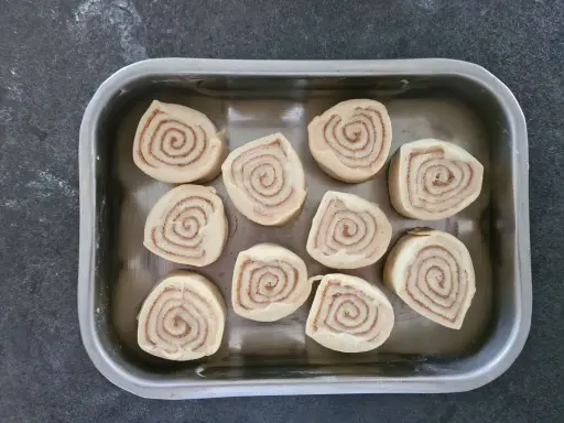 Dix roulés à la cannelle prêts pour la cuisson, une étape clé de la recette de cinnamon rolls.