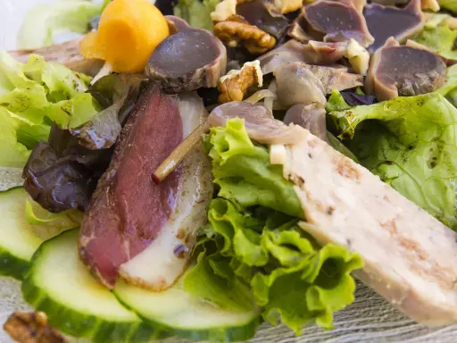 Salade landaise généreuse avec magret de canard fumé, gésiers confits, noix et légumes croquants. Un délice du Sud-Ouest.