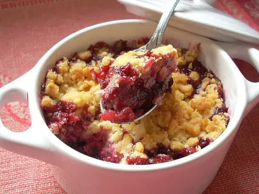 Cuillère de crumble fruits rouges, un délice croustillant et fruité dans un ramequin blanc.