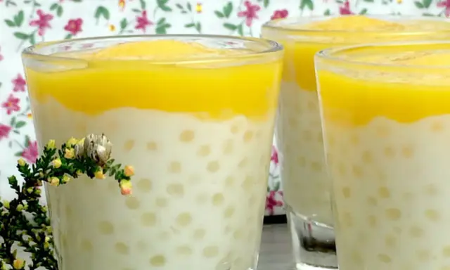 Trois verres de tapioca au lait de coco, surmontés d'une purée jaune, avec une petite branche de bruyère en premier plan.