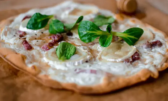 Délicieuse tarte flambée végétarienne garnie de fromage de chèvre, oignons et herbes fraîches.