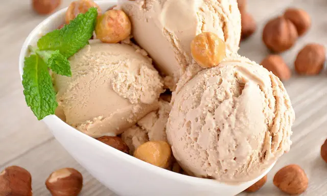 Gourmande recette glace noisette italienne. Boule crémeuse, garnie de noisettes grillées et d'une touche de menthe fraîche.